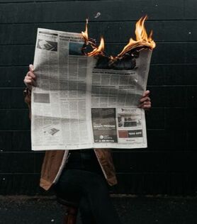 Person reading a newspaper that is on fire- Families Advocating for Chemical & Toxics Safety